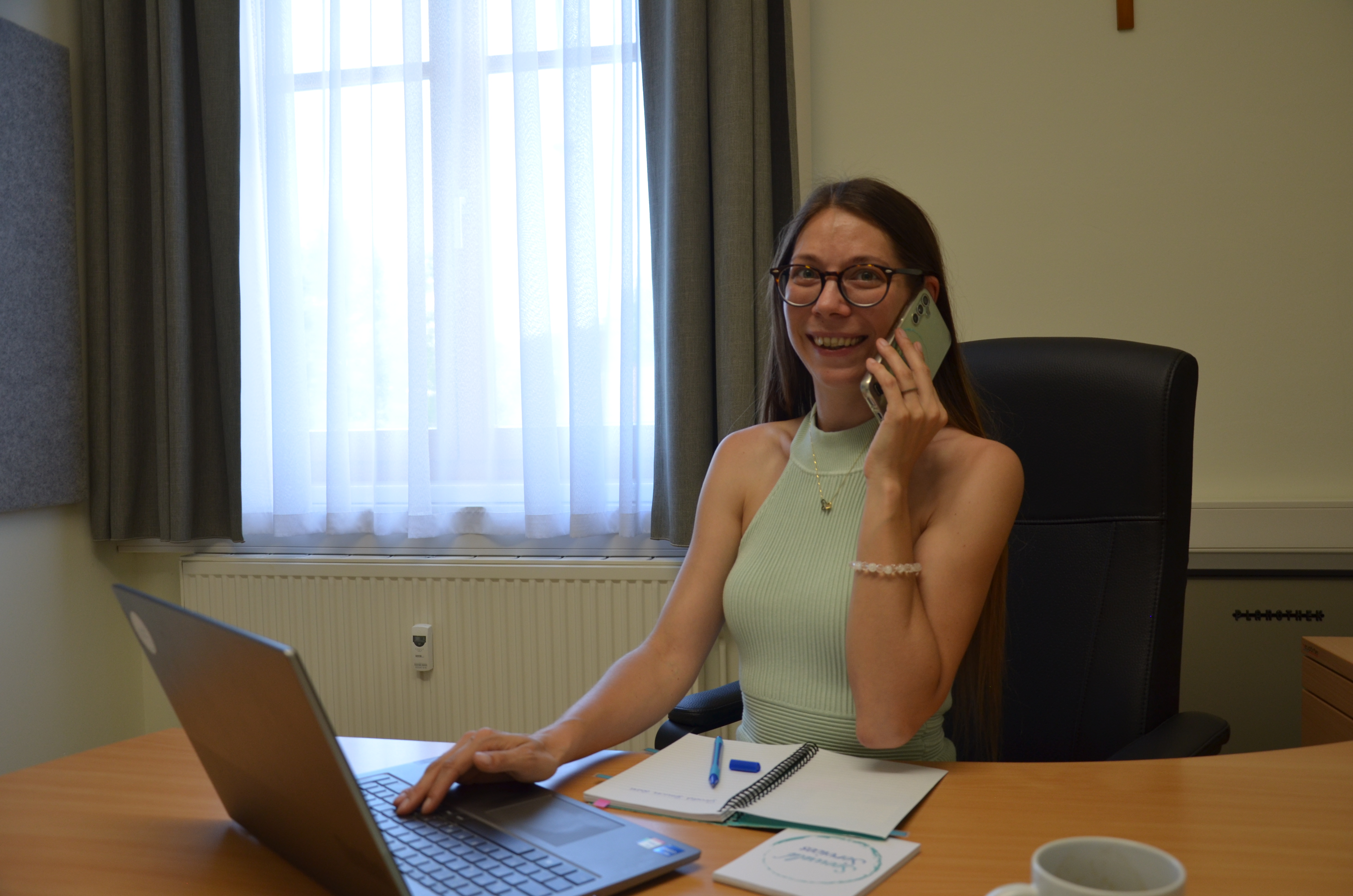 Petra Seewald, MSc, von Seewald Services GmbH sitzt am Schreibtisch mit Laptop und spricht lächelnd am Telefon, Symbol für persönliche BMD-Kundenbetreuung.