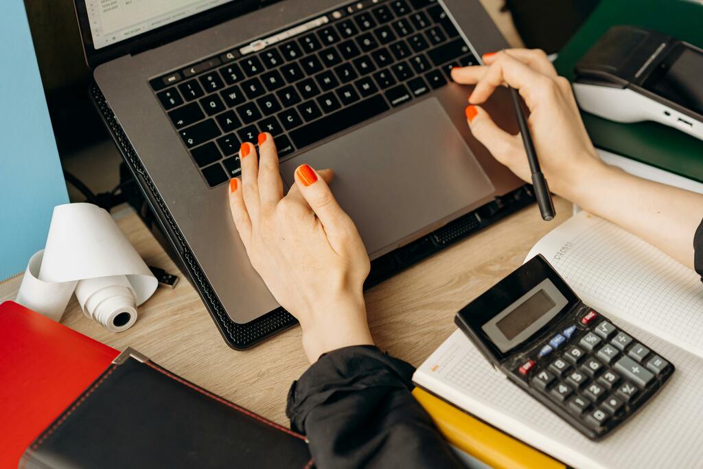 Hände auf Laptop-Tastatur neben Taschenrechner, Symbolfoto für Personalverrechnungsservice der Seewald Services GmbH.