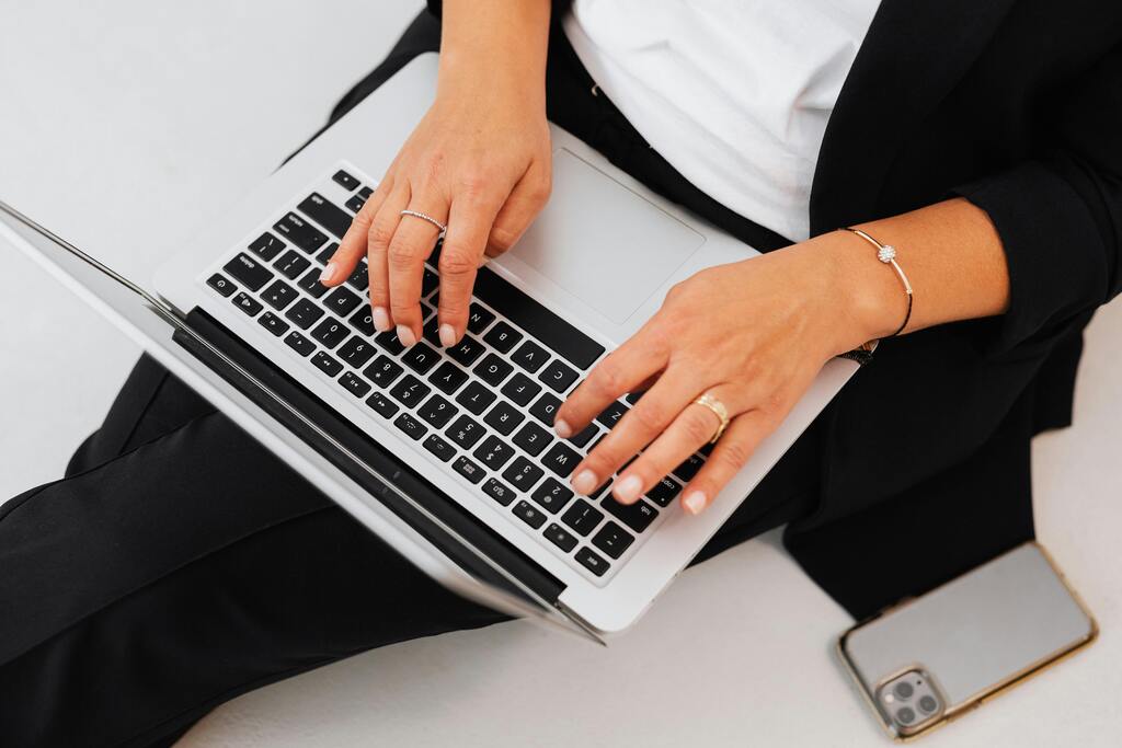 Nahaufnahme von Händen auf Laptop-Tastatur neben Smartphone, Symbolfoto für Digitalisierung & Automatisierung mit Seewald Services GmbH.